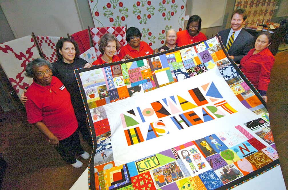 Norwalk Has Heart Quilt - Peace by Piece quilters with David Westmoreland, Norwalk Historical Society president at the unveiling of the Norwalk Has Heart Quilt, which was created by Peace by Piece with assistance from hundreds of local residents of all ages. From left are: Ernestine Cobb, Anna Veccia, Lizzy Rockwell (who designed the quilt), Betty Mungo, Rita Phillips, Viola Sears, Westmoreland and Eisabell Garcia. Photo credit: The Norwalk Hour